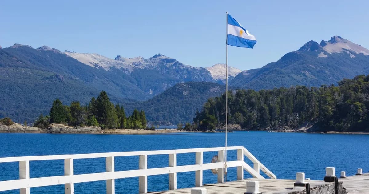 Argentine flag over a lakeside pier in Patagonia, with the Andes behind, Argentina
