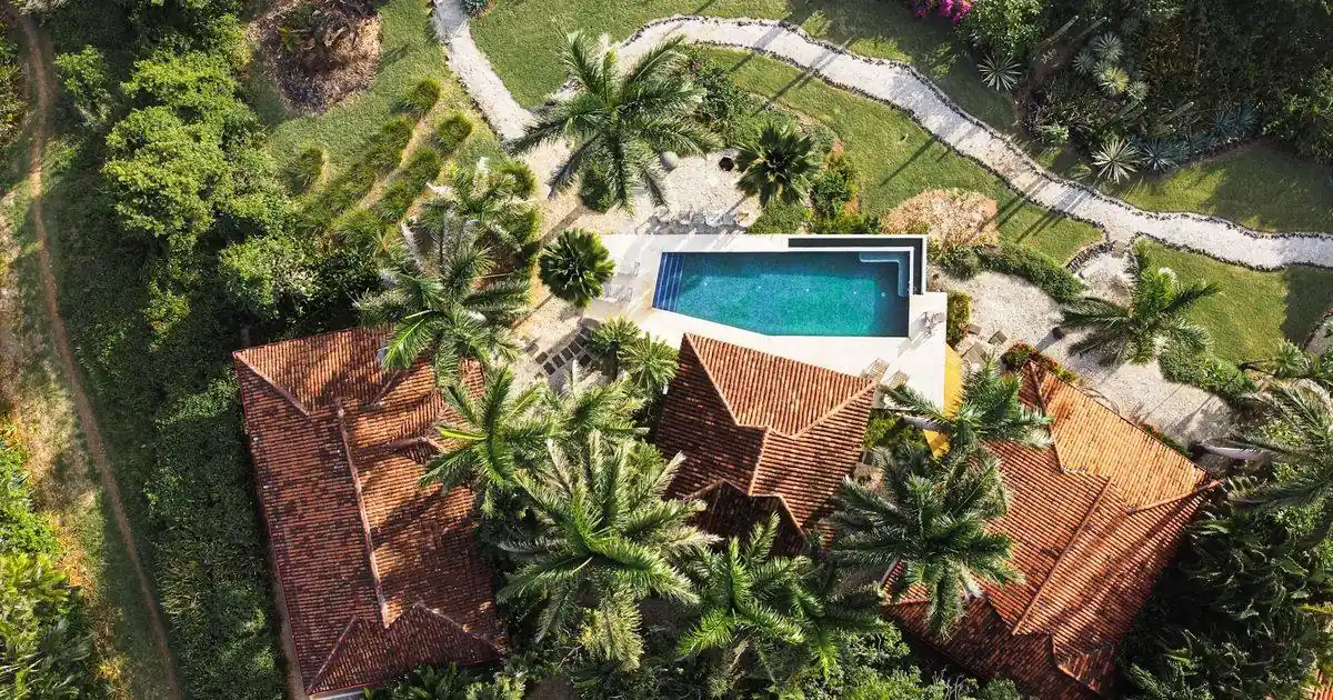 An aerial view of a tiled-roof villa with a pool among palm trees in Costa Rica
