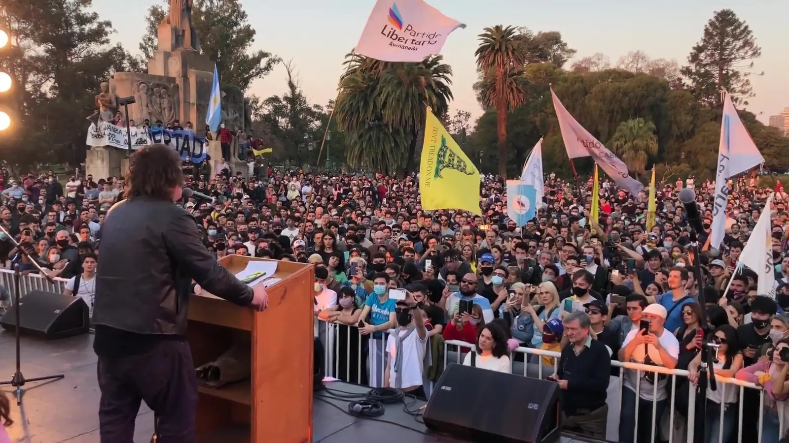 Javier Milei speaks from a stage to a large crowd of supporters waving flags at a La Libertad Avanza rally, Argentina